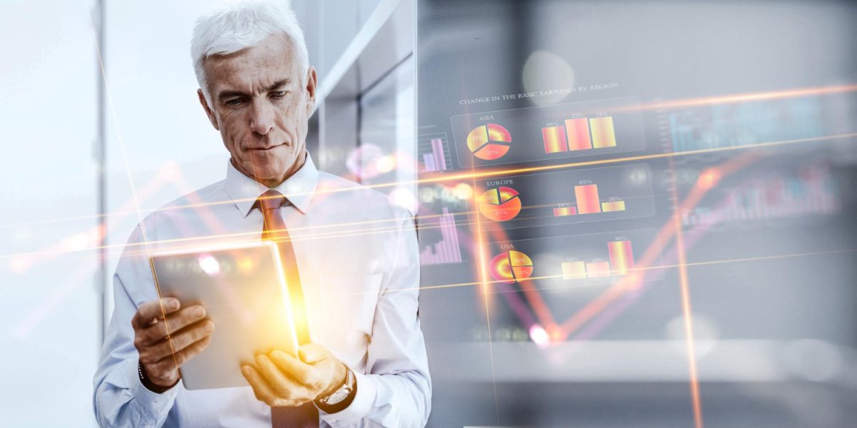 Homem de meia idade segurando um tablet com as mãos enquanto há dados e gráficos ao fundo, trazendo o contexto do capital estratégico dos dados.