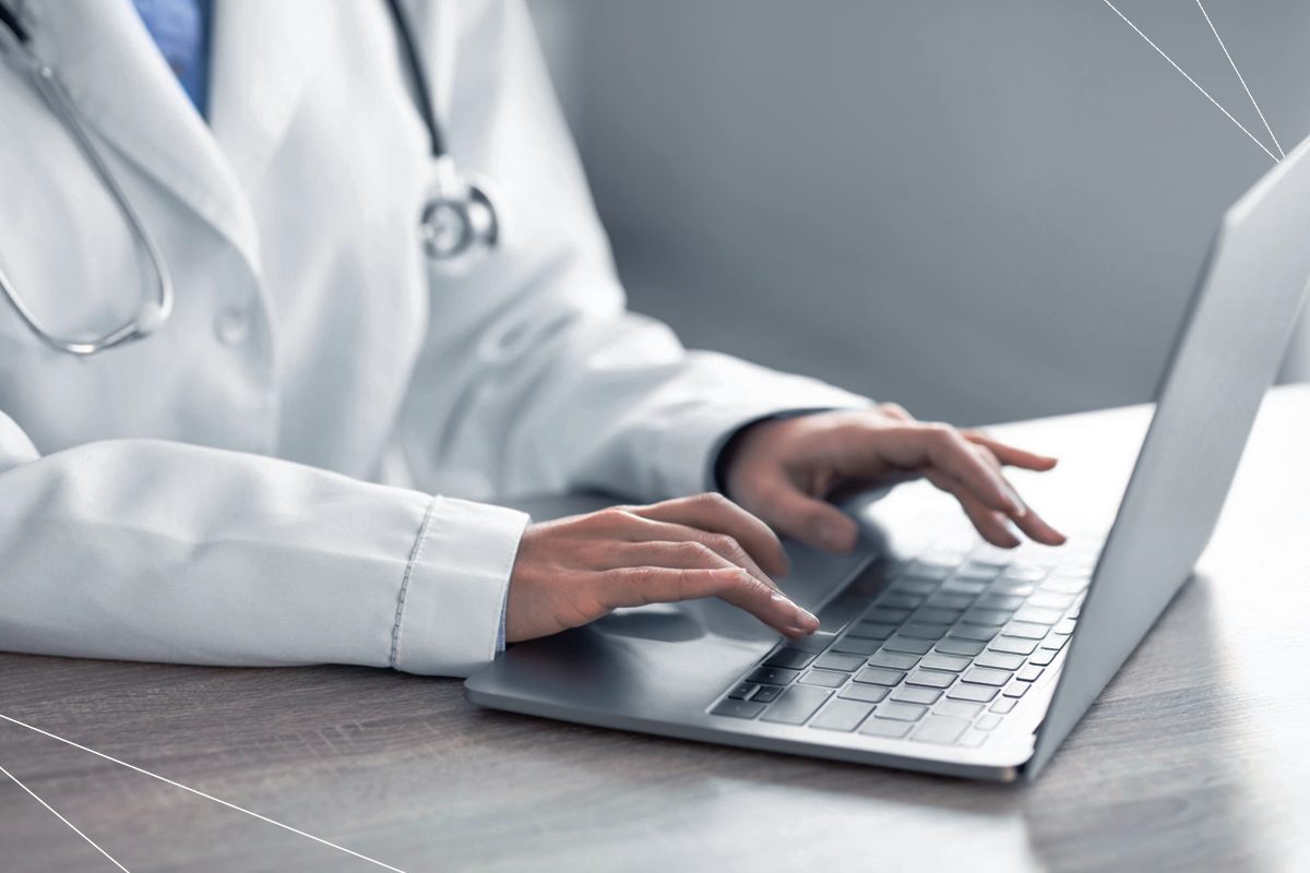 Médico digitando no teclado de um notebook, trazendo o contexto de fraudes nos planos de saúde.