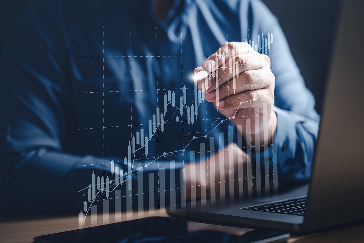 A mão de uma pessoa segura uma caneta na direção de uma tela holográfica com um gráfico crescente, trazendo o contexto do crescimento do mercado de seguros no Brasil.